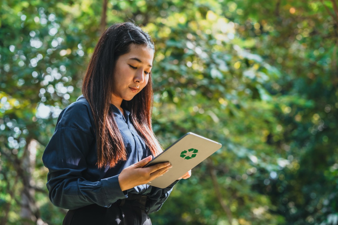 Une femme professionnelle tenant un ordinateur portable avec le logo ESG (Environnement, Social, Gouvernance) affiché à l'écran,